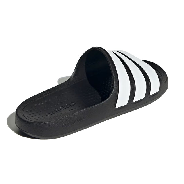 A pair of black and white adidas Adilette Flow slides.