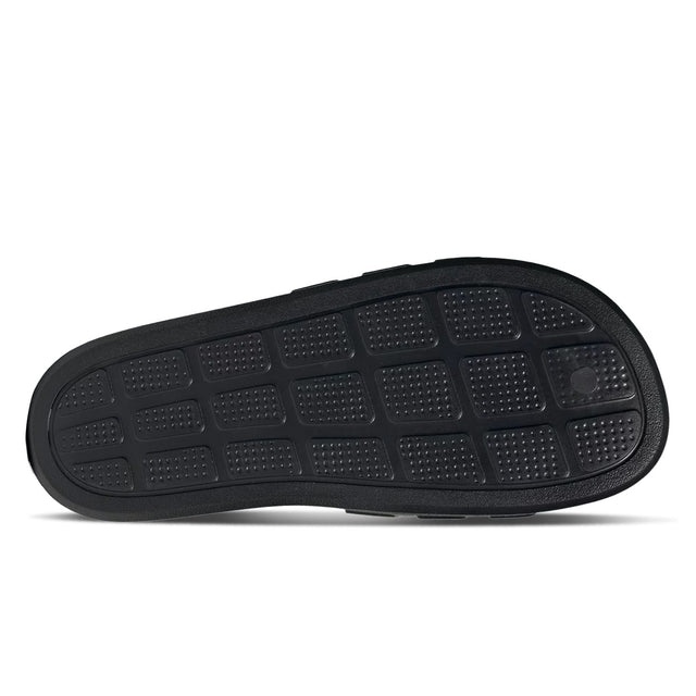 A pair of black and white adidas Adilette Flow slides. - outsole view