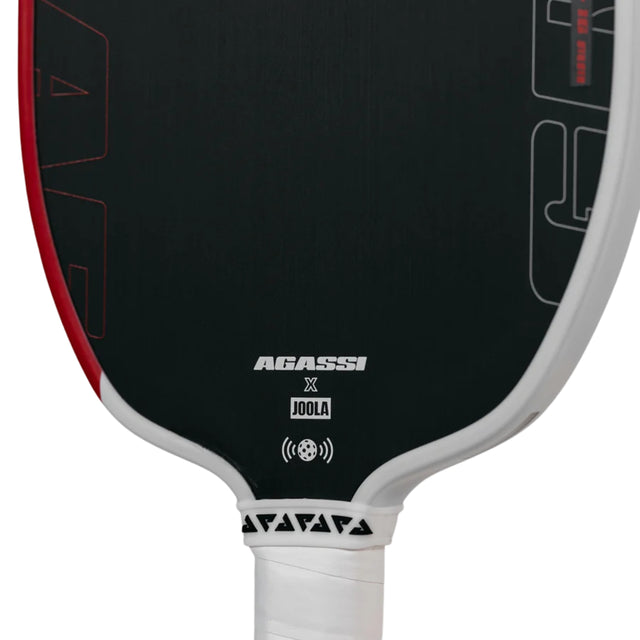 Close-up of a pickleball paddle with Agassi and Joola branding on a black background.