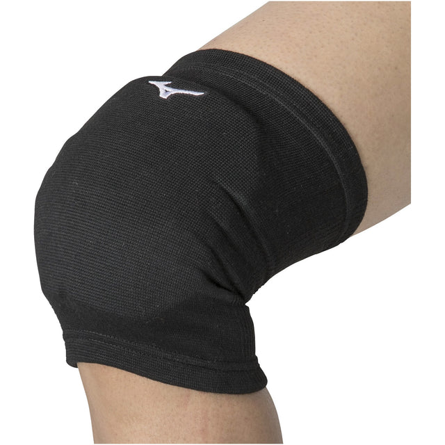 A black Mizuno knee pad worn on a person's leg, featuring a snug fit and the Mizuno logo on the front.