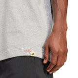 Person wearing a gray Adidas shirt with a close-up of the brand logo on the sleeve.